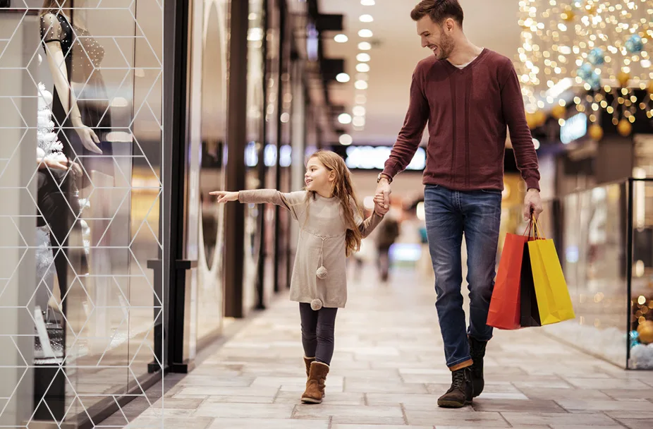 photo of man holding little girl's hand while shopping in a mall