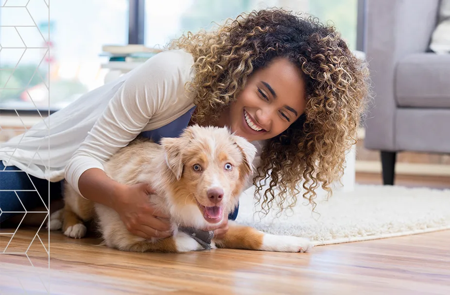 photo of smiling woman holding puppy on floor